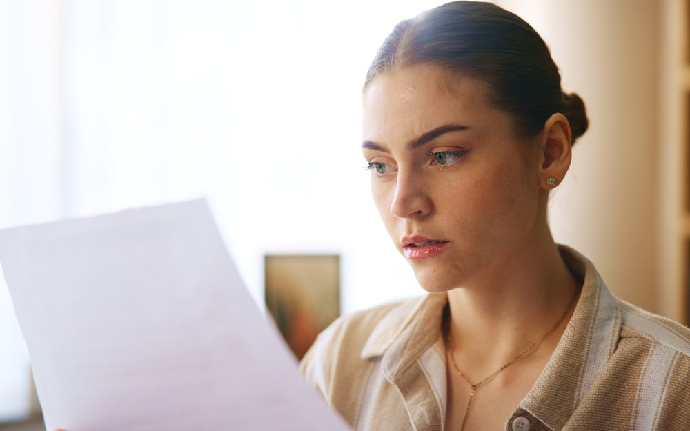 Woman holding an employment contract, reviewing 5 critical clauses before signing