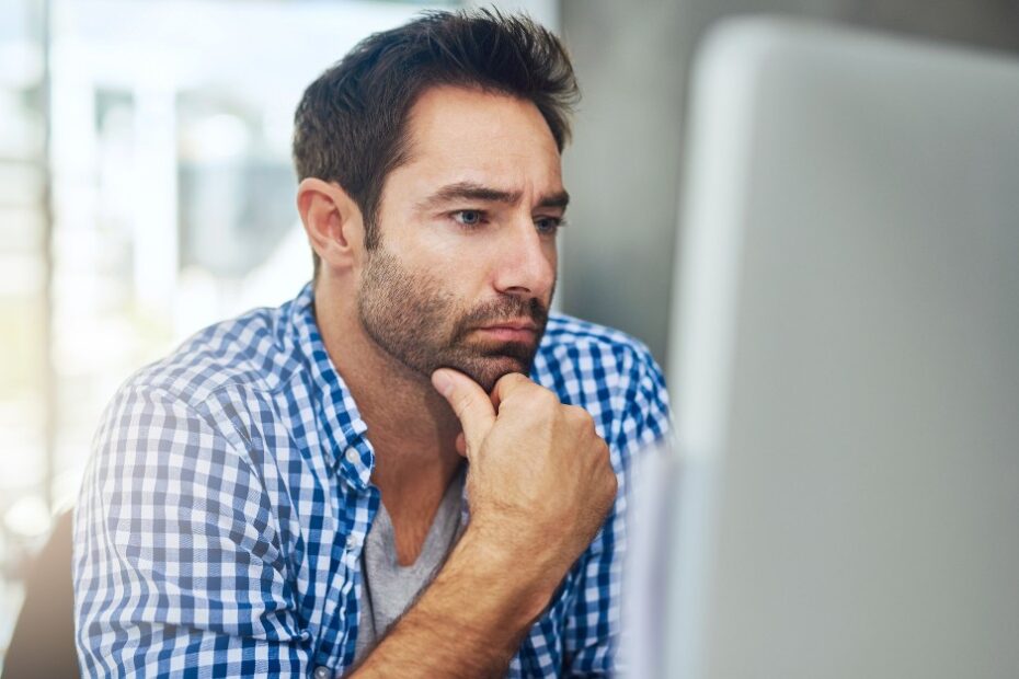 Man thinking in front of the computer about CGT Rule for Deceased Estates