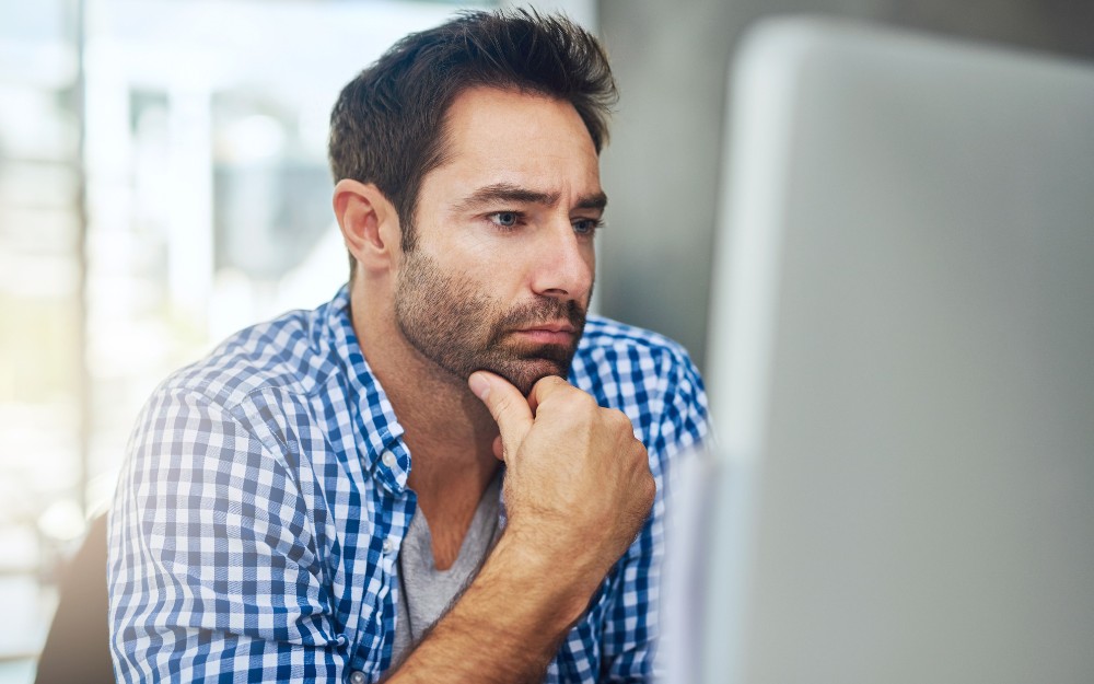 Man thinking in front of the computer about CGT Rule for Deceased Estates