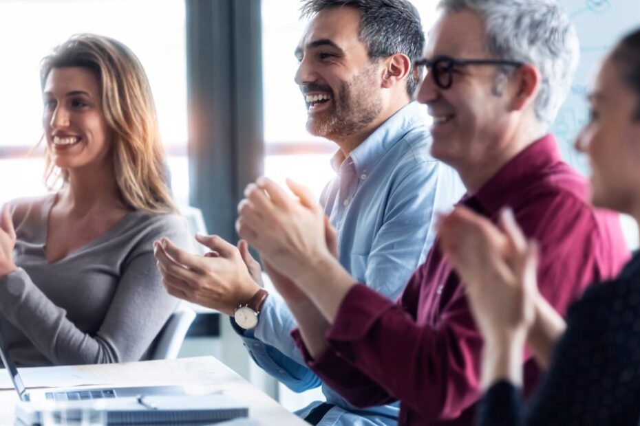 Four people in a meeting clapping because of change